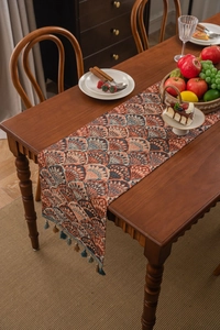 Close-up of thick jacquard table runner with ginkgo leaf pattern and colorful tassels
