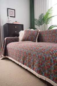 Dettaglio del copridivano jacquard colorato con frange e cuscino coordinato in tessuto