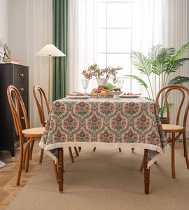 Detail of vintage floral jacquard tablecloth with elegant fringe tassels in a cozy room