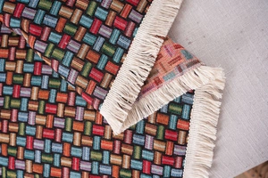 Dettaglio del copridivano spesso in jacquard con trama colorata e frange color crema