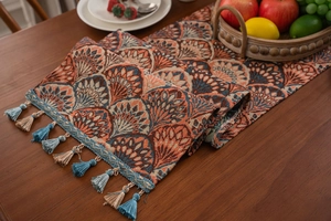 Detail of bohemian mandala jacquard table runner with blue tassels on wooden surface