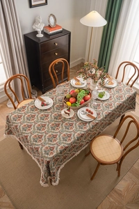 Close-up of vintage floral jacquard tablecloth texture with elegant cream fringe tassels