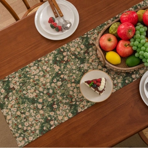 Floral table runner in dark green with vintage tassels on a rustic wooden dining table