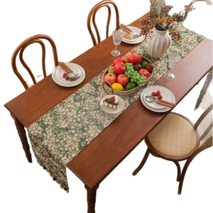 Floral green table runner with elegant fringe tassels on a rustic wooden dining table