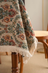 Close-up of vintage floral jacquard tablecloth with thick texture and cream tassels