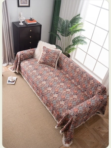 Detail of bohemian sofa cover with ethnic peacock pattern and white decorative fringe tassels