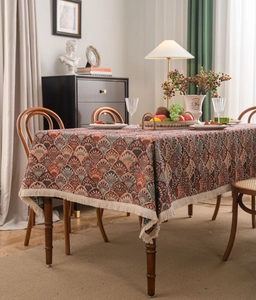 Detail of bohemian jacquard tablecloth featuring red and blue patterns with cream tassels