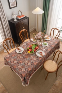 Detail of bohemian jacquard tablecloth with orange floral pattern and white tassel edges