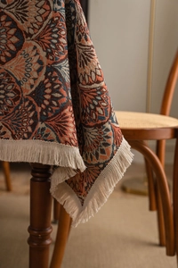 Detail of bohemian jacquard tablecloth featuring orange geometric patterns and beige tassels