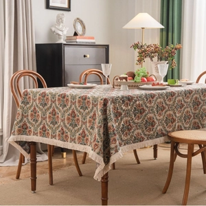 Vintage floral jacquard tablecloth with fringe trim on a rectangular dining table