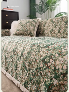 Close-up of green floral sofa cover fabric with fringe tassels and matching pillows