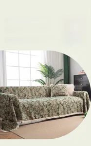 Close-up of green floral jacquard sofa cover with elegant white tassel fringe edges