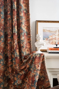 Detailed view of jacquard floral pattern on orange thick curtains with fringe trim