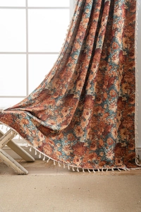 Detail of floral jacquard curtains with orange sunflowers and elegant cream tassels