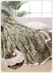Detail of forest green floral knit throw blanket with decorative cream fringes and texture