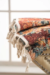 Close-up of orange floral jacquard curtain fabric with decorative white fringe tassels