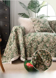 Close-up of thick green floral sofa cover fabric with fringe edges and woven texture