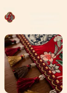 Detail of red table runner with floral pattern and colorful handmade tassel on wood