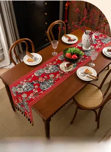 Close-up of red table runner with blue and white porcelain pattern and decorative tassel