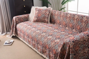 Detail of bohemian chenille sofa cover with retro scale patterns and beige tassels
