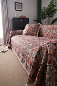 Detail of bohemian sofa cover featuring orange fan textures and fringe tassels