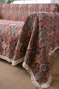 Detail of bohemian sofa cover featuring colorful geometric patterns and elegant tassels