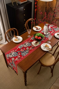 Detail of red jacquard table runner with blue and white porcelain pattern and tassels
