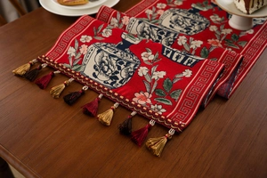 Macro detail of red Chinese jacquard table runner with porcelain floral patterns and tassels