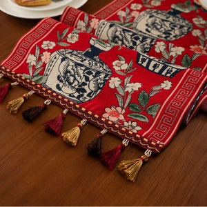 Red jacquard table runner with blue and white porcelain floral pattern and fringe