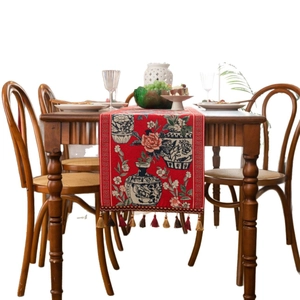 Red jacquard table runner with blue and white porcelain pattern and colorful tassels