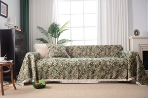 Detail of green floral sofa cover with white fringe tassels and matching pillows