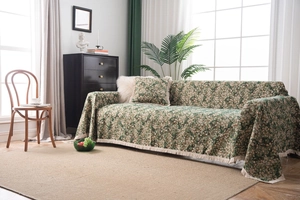 Close-up of vintage green floral sofa throw cover with elegant beige fringe tassels