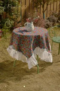 Close-up of a satin tablecloth with colorful geometric patterns and white lace ruffles