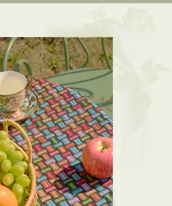 Detailed weave of a colorful geometric jacquard tablecloth in a rustic French garden setting