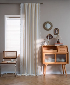 Detail of white linen curtain with yellow chain embroidery and fine tassel edges