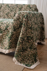 Detail of green floral sofa cover fabric with white daisy patterns and cream tassels
