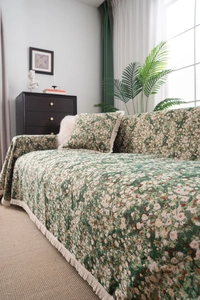Close-up of green sofa cover with white daisy patterns and cream tassel edge detail