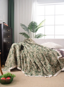 Close-up of green floral chenille sofa cover with decorative beige fringe tassels