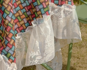 Close-up of colorful woven tablecloth featuring elegant white floral lace ruffle edges