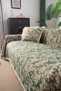 Detailed texture of thick green floral sofa cover with white tassels and matching cushion