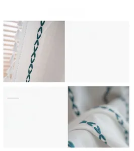 Détail d'un rideau blanc avec broderie losange verte et pompons blancs élégants