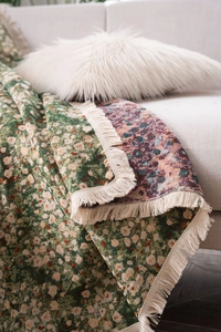 Detail of forest green vintage floral sofa throw with white tassels and thick fabric texture