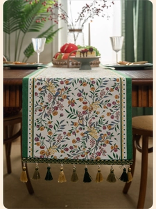 Detail of floral and bird jacquard table runner with decorative multi-color tassels