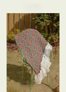 Outdoor view of colorful woven tablecloth with white lace edges on a green chair