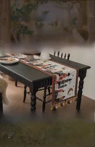 Dettaglio del runner da tavolo beige con motivi di castelli vintage e nappe colorate