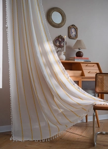 Detail of bohemian cream curtain with yellow geometric stripes and handmade fringe trim