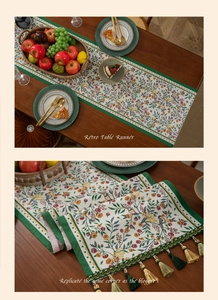Detail of retro table runner with green tassels and floral bird pattern on wooden table