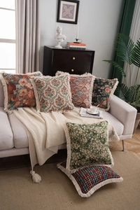 Detail of high-quality jacquard pillows with vintage fringe and knitted throw blanket
