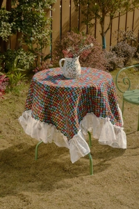Detailed close-up of woven geometric tablecloth featuring elegant white wide lace ruffles