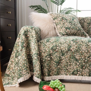 Floral green sofa cover with white fringe tassels and matching pillows in cozy interior